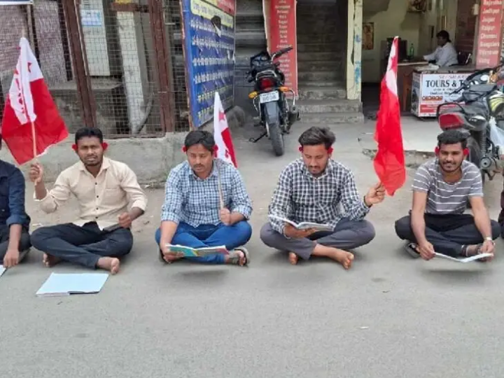 చేతిలో బుక్, చెవిలో పూలతో నిరసన