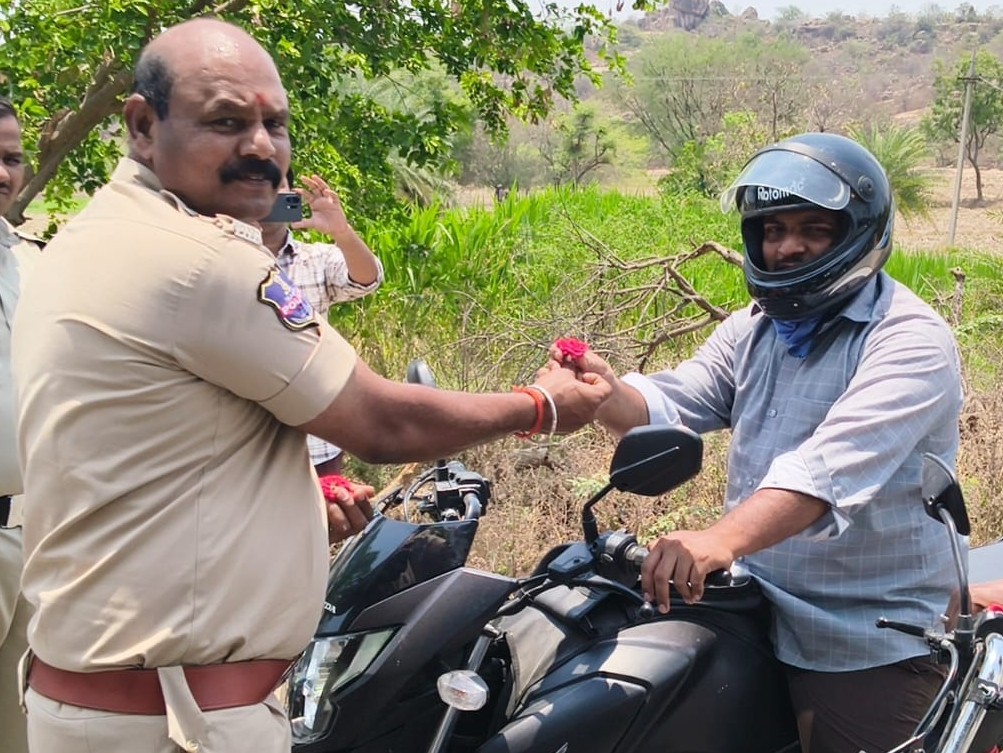 భద్రత పాటిస్తున్న వాహనదారులకు పూలు అందించిన ఎస్సై